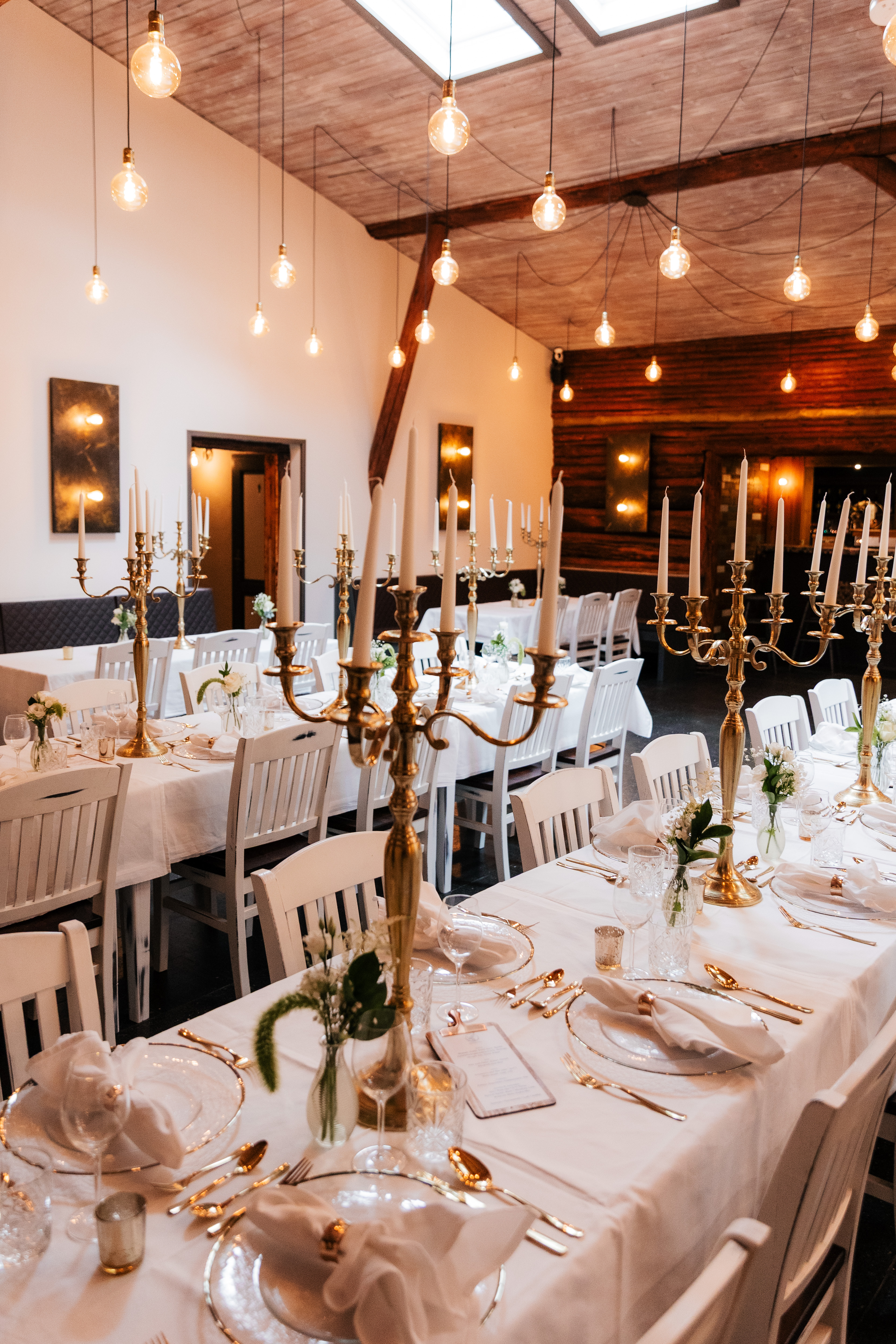 Lange Hochzeitstafel im Speiseraum mit weissen Stuehlen und Kronleuchter.