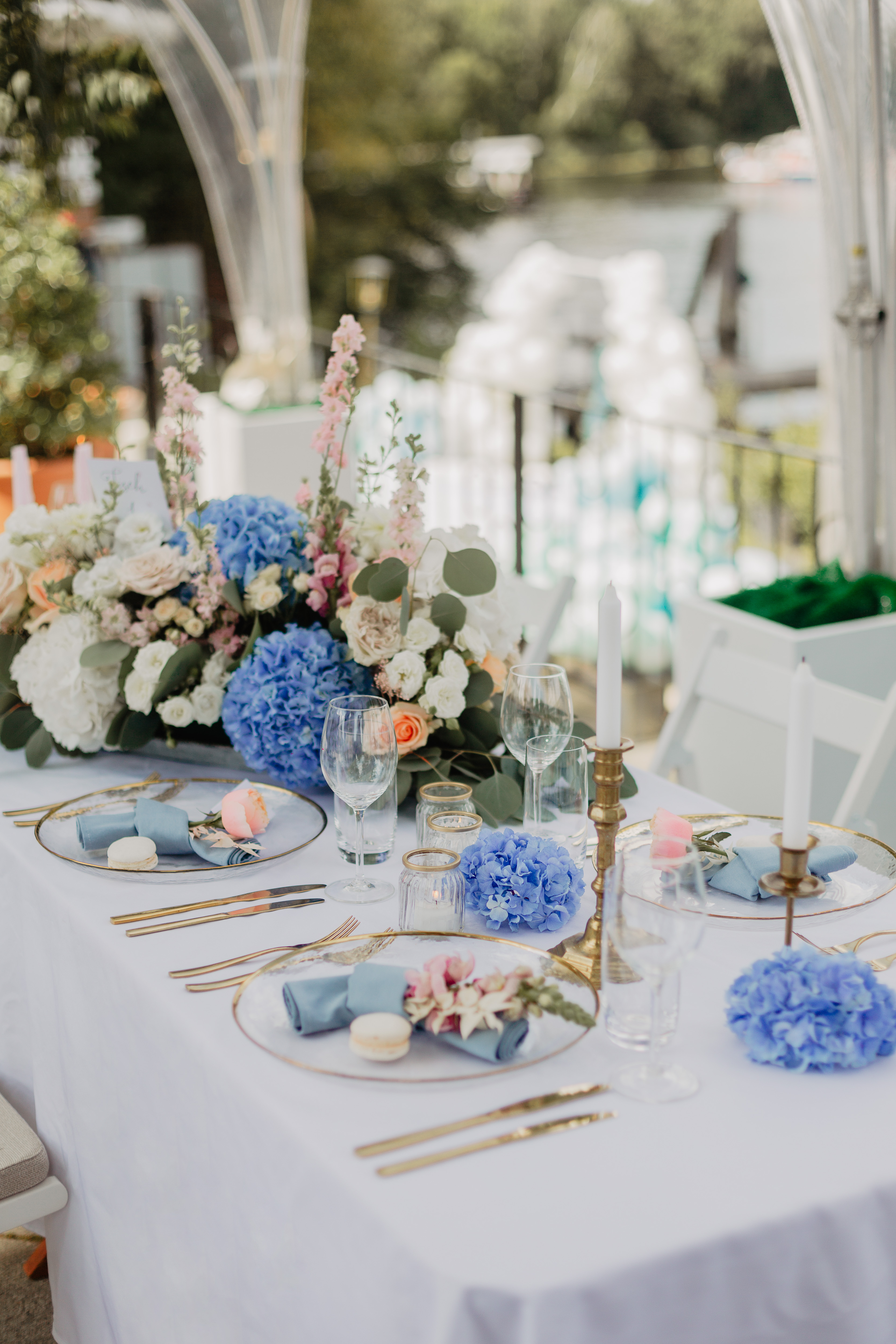 Schmale Hochzeitstafel mit blau-weisser Dekoration und Blick ins Gruene.