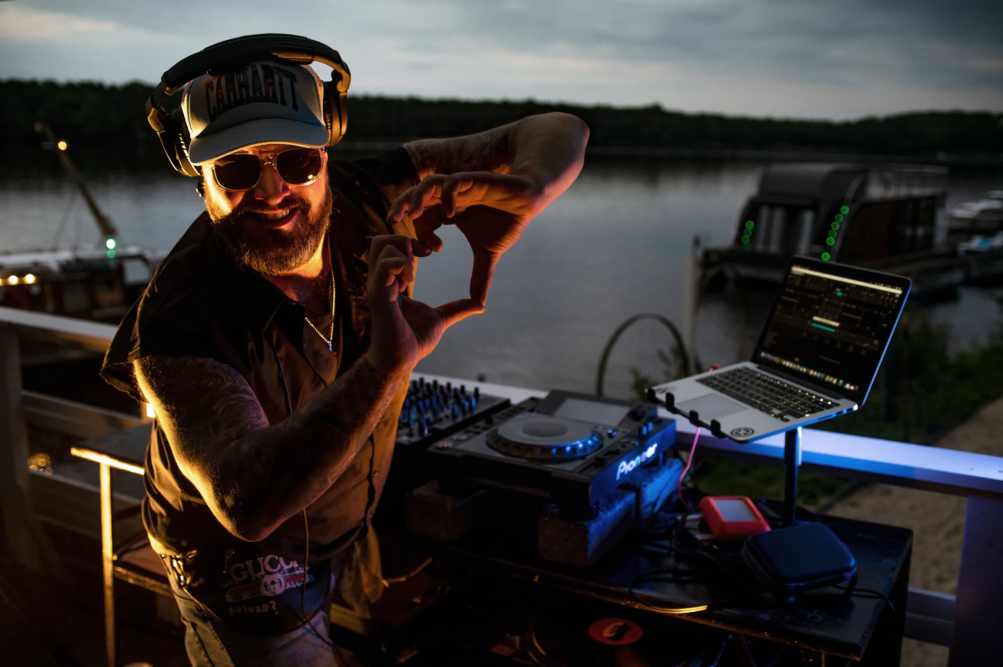 DJ performt nachts mit Lichttechnik vor der Eventlocation am See.