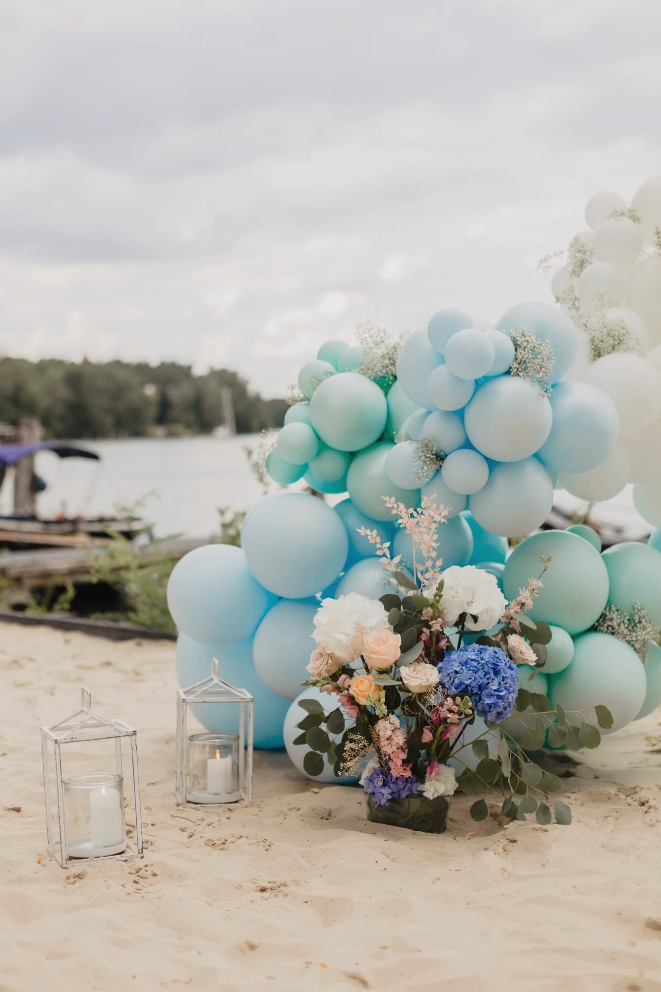 Pastellfarbene Ballondekoration auf dem Sandstrand direkt am See.