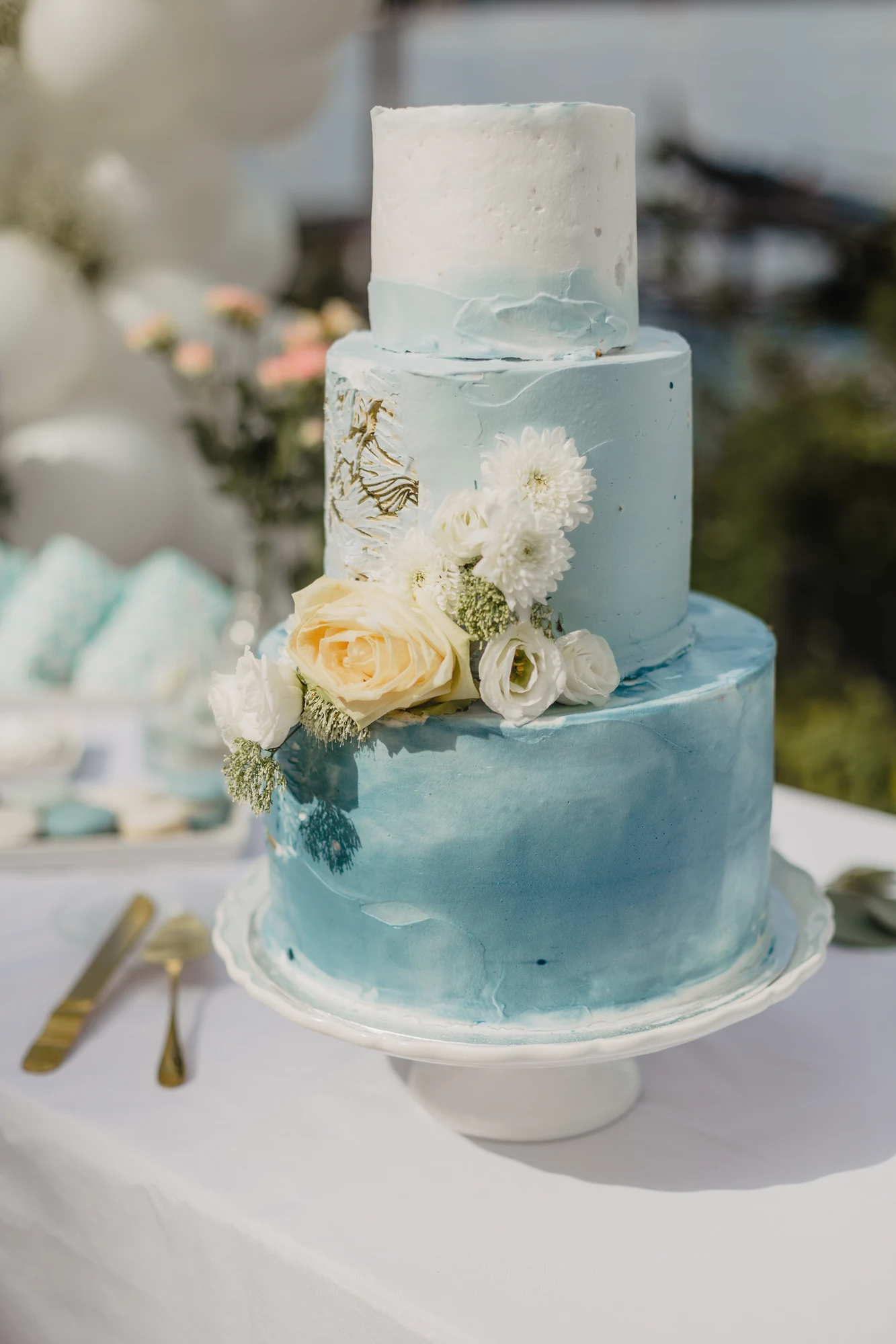 Mehrstoeckige Hochzeitstorte mit blauen Farbverlaeufen und Bluetendekor.
