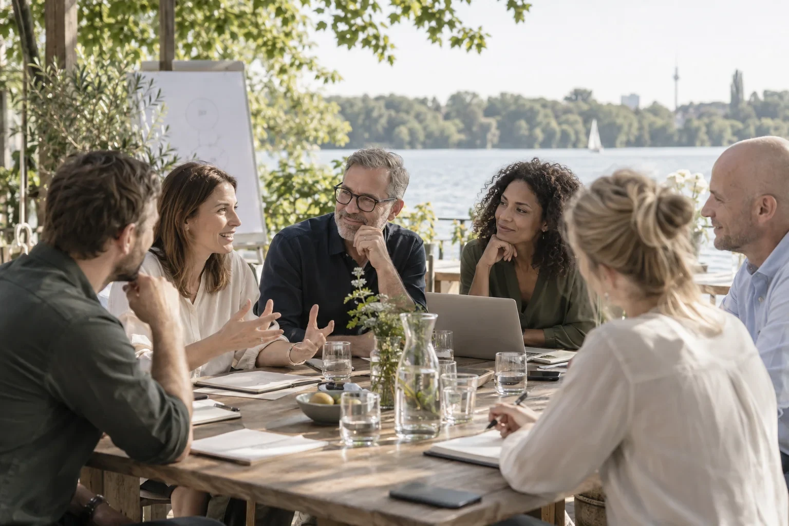 KI-Visualisierung: Kolleginnen und Kollegen tauschen sich an einem Tisch am See aus