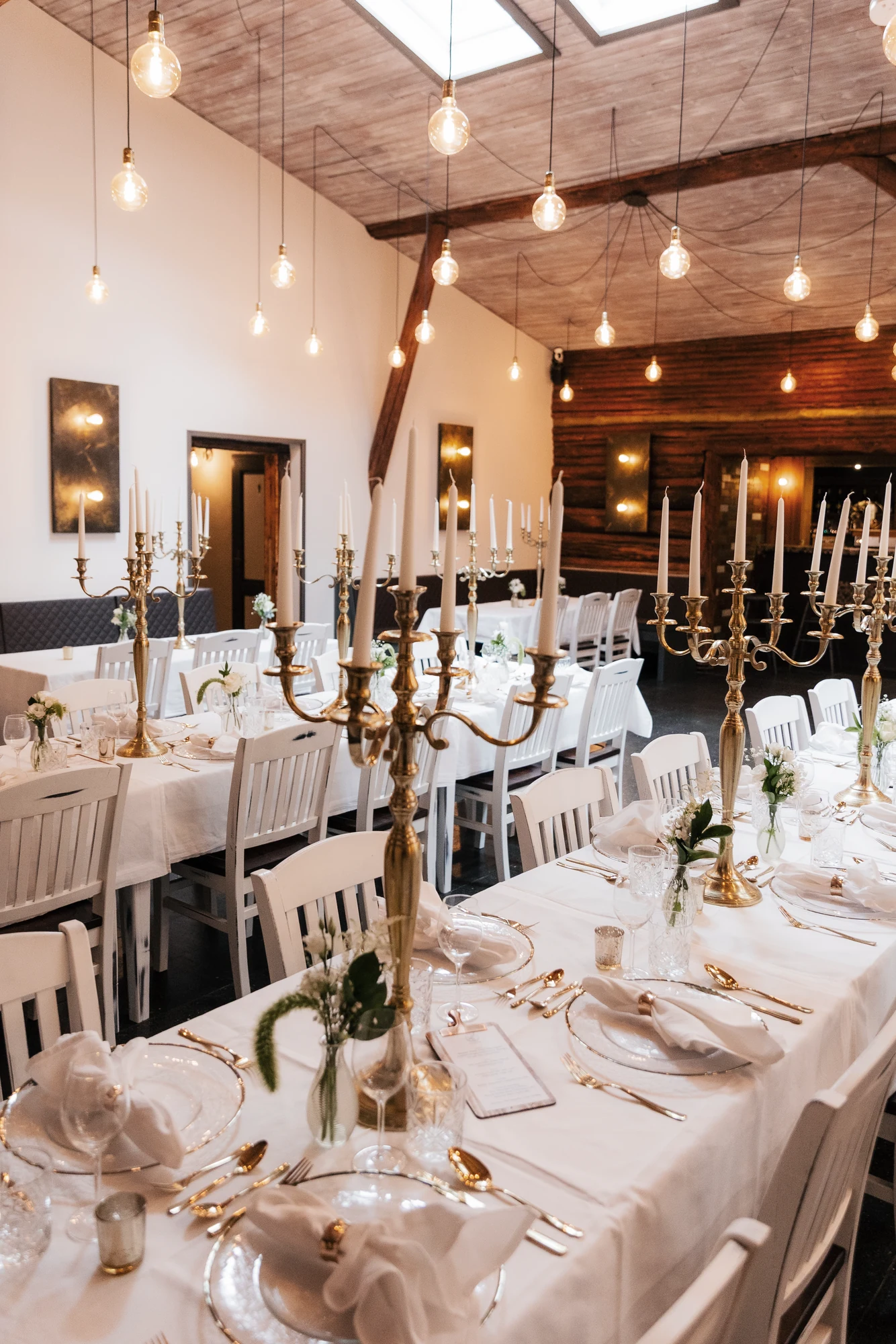 Lange Hochzeitstafel im Großen Saal mit weissen Stuehlen und Kronleuchter.