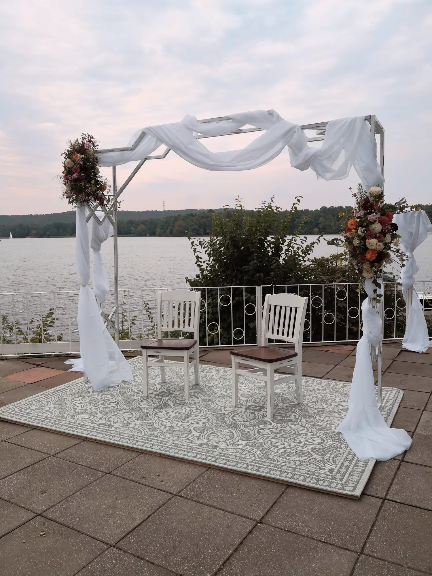 Weisser Traubogen mit Blumenschmuck auf der Terrasse direkt am Seeufer.