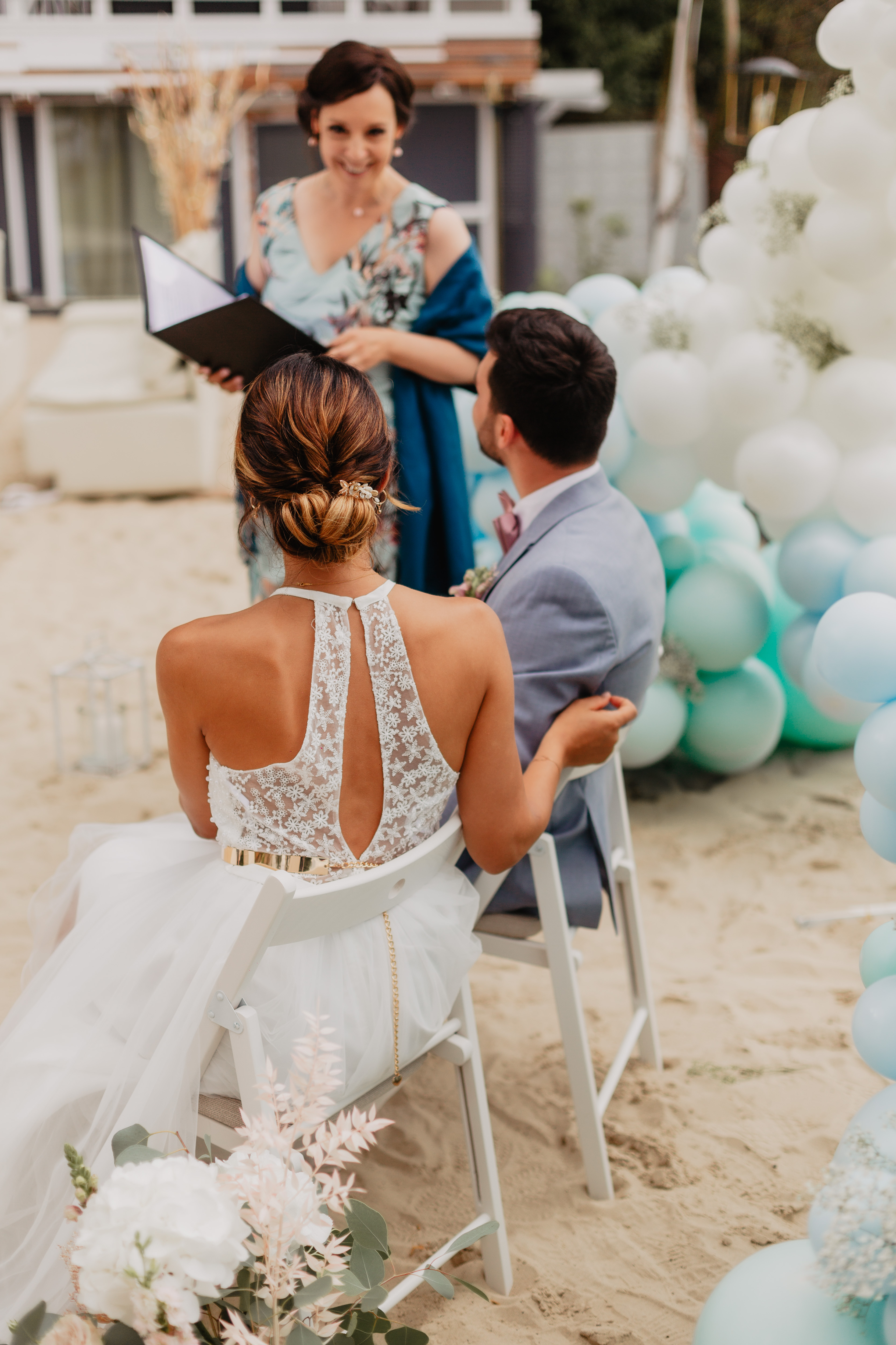 Strandtrauung mit Brautpaar, Traurednerin und pastellfarbener Ballondeko am See.